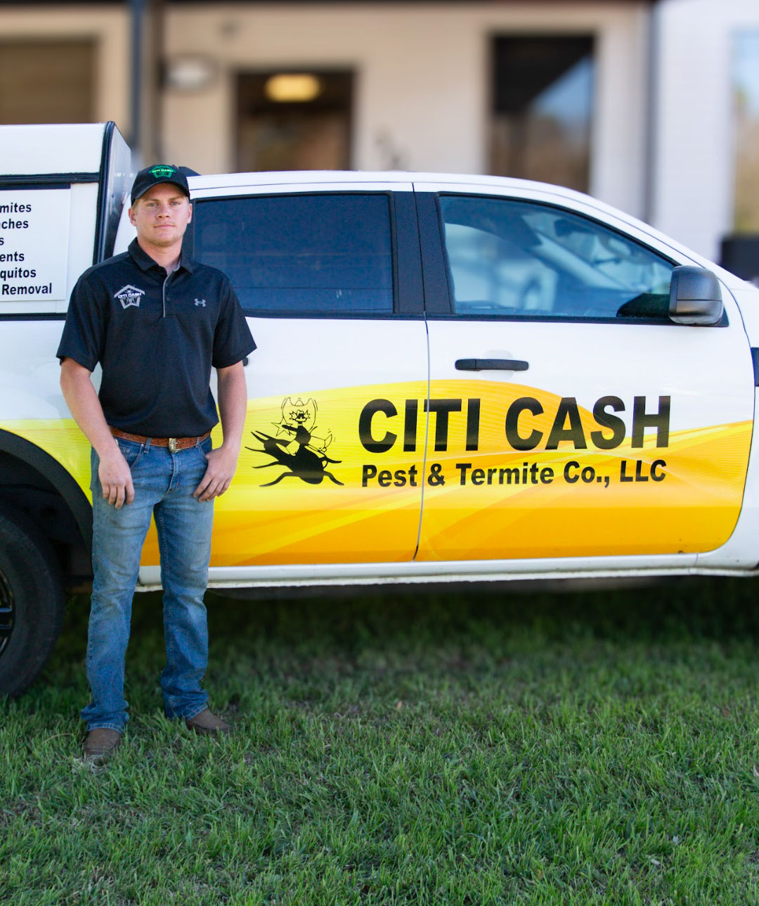 Man in a black shirt and cap stands by a Citi Cash Pest & Termite Co., LLC truck parked on grass.